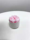 Mini pink preserved peony standing on a round white table
