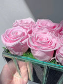 Close view of pink preserved roses and moss inside the mirrored vase