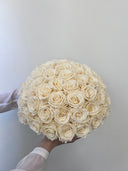 Amelie preserved rose arrangement held to the side against a pale wall