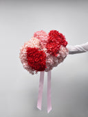 Pink Parfait bouquet held at arm's length against a pale wall
