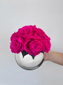 Selene preserved rose arrangement held in one hand against a pale wall