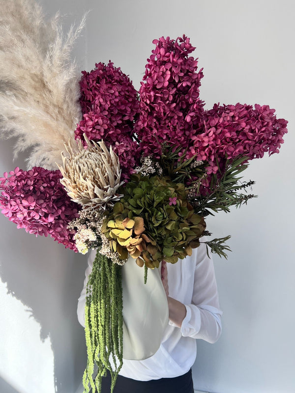 Sienna arrangement of boysenberry and olive preserved hydrangea with pampas in a tall white vase