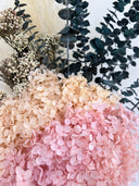 Close-up of blush pink preserved hydrangea beneath dark eucalyptus and pampas