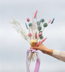 A pastel bouquet of dried and preserved flowers with bunny tails, tied with pink ribbon