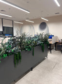 A grey planter box of preserved foliage and trailing amaranthus dividing an open-plan office