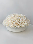 A dome of ivory preserved roses in a low white bowl