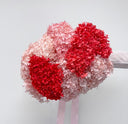 A bouquet of pink and red preserved hydrangeas with a pink ribbon