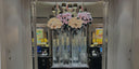 Tall glass vases of pink and peach preserved roses at a store entrance