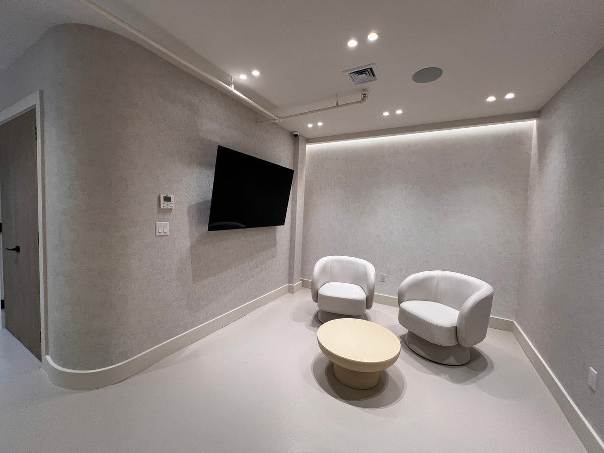 Before: a Vivant Mind waiting room with two chairs, a side table and a television, and no plants