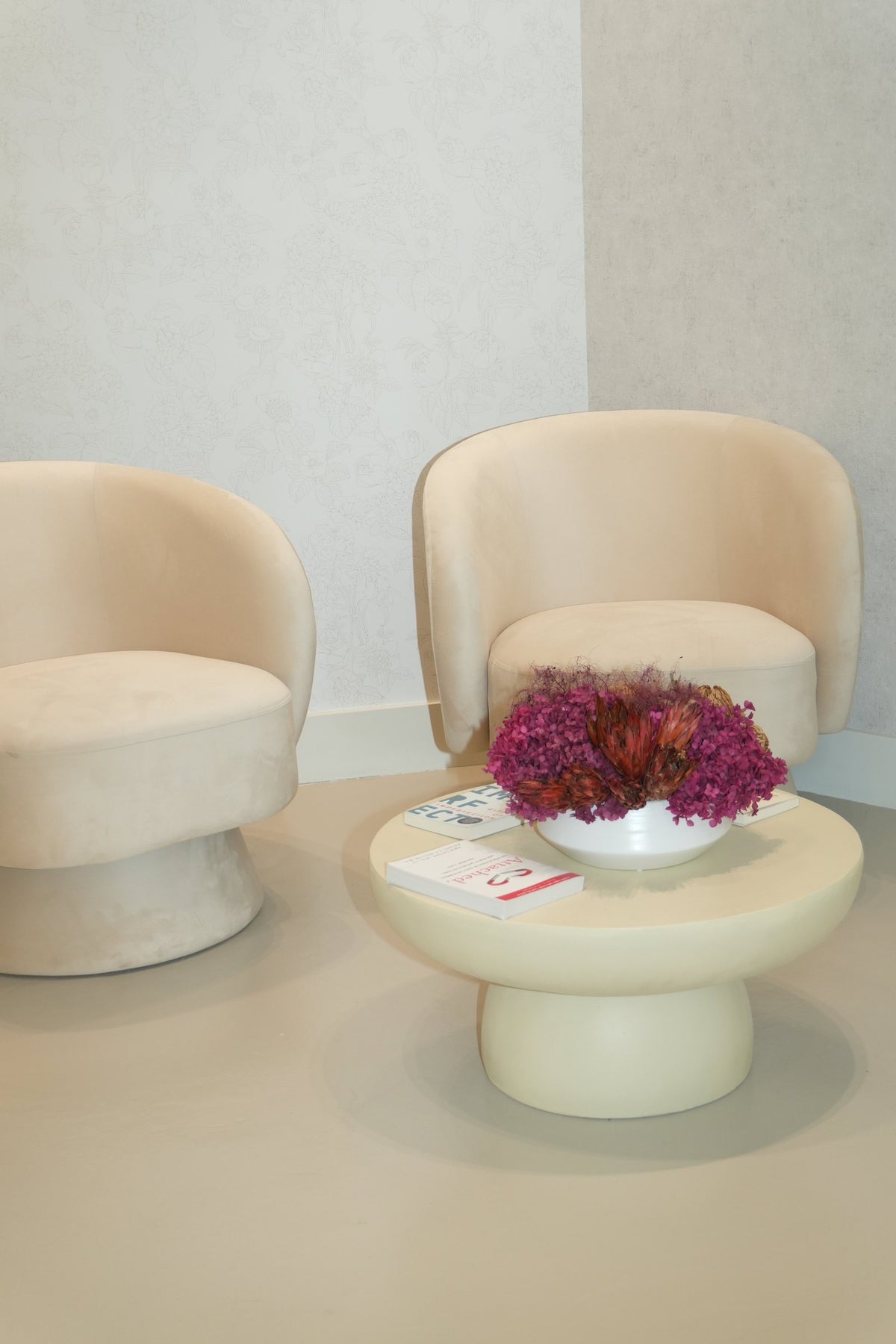 Two cream chairs around a low table with a bowl of preserved magenta flowers at Vivant Mind
