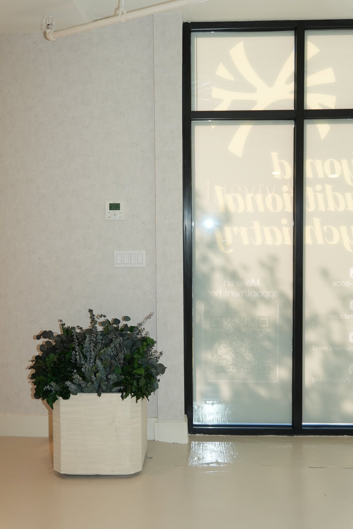A planter of preserved foliage beside the glass entrance doors at Vivant Mind
