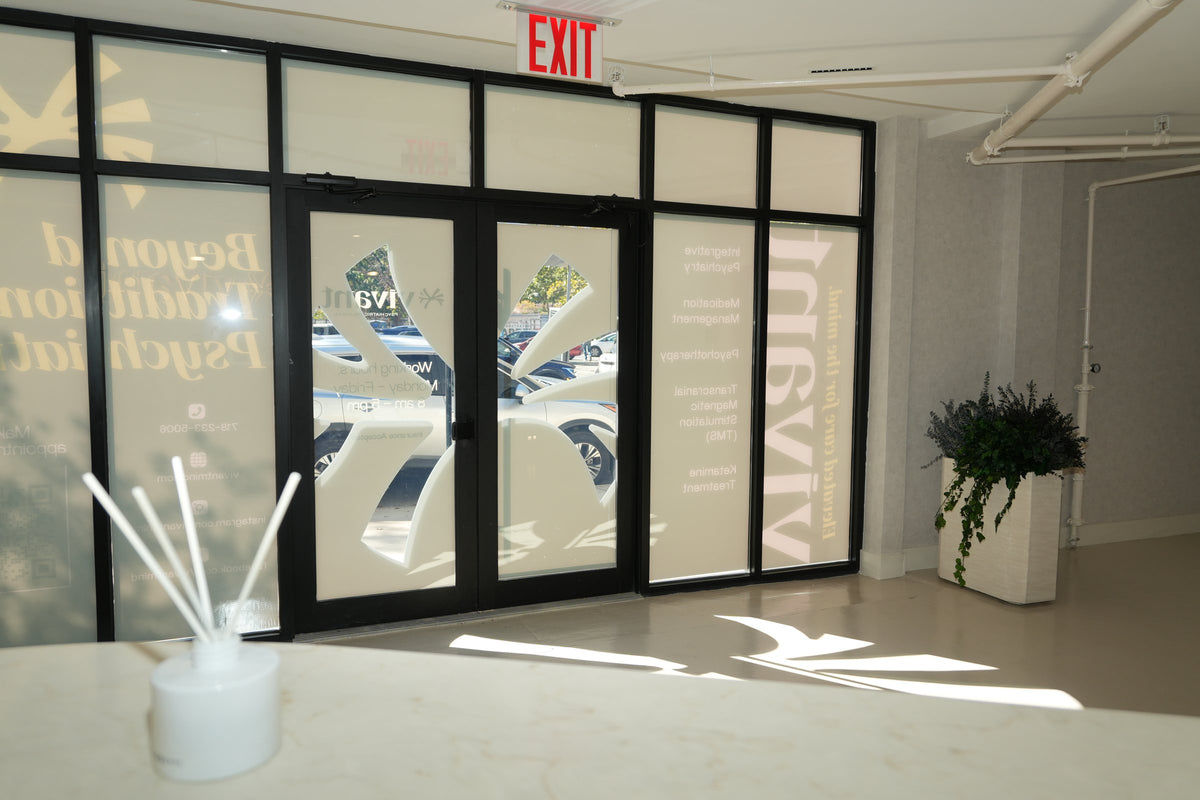 The Vivant Mind entrance, with a planter of preserved foliage beside the frosted glass doors