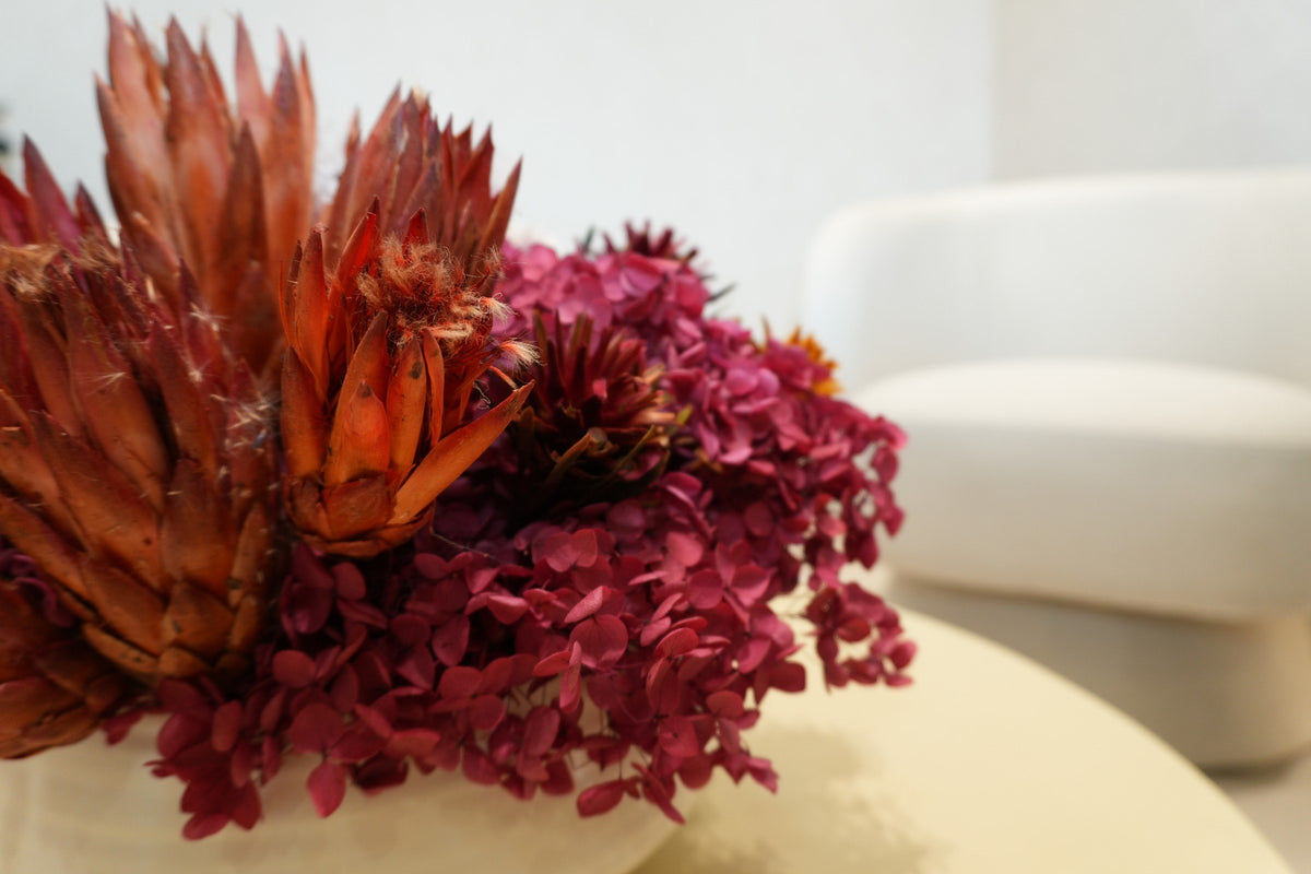 Close-up of preserved rust protea and magenta hydrangea on a round table in a Vivant Mind waiting area
