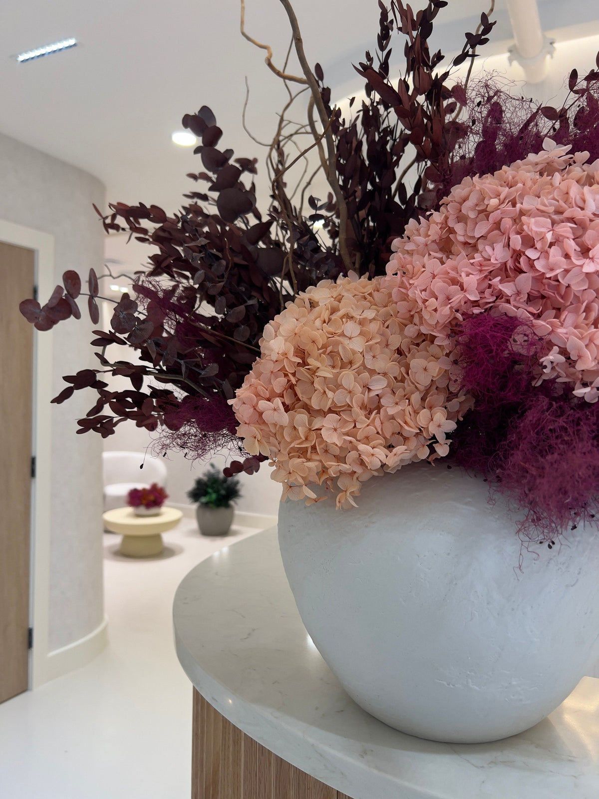 The preserved hydrangea arrangement at the end of the Vivant Mind reception desk, the corridor and a waiting corner beyond