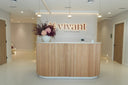 The Vivant Mind reception: a wood-slat desk under the lit vivant sign, a preserved arrangement of pink hydrangea and plum foliage at one end